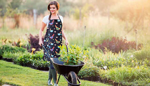 woman outdoors wearing black apron and holding wheel barrow