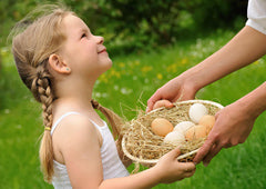 Young girl holding basket of chicken eggs in backyard