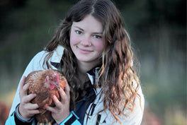 young woman holding an isa brown chicken