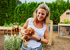 woman holding chicken in backyard