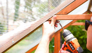 man wearing sunglasses assembling chicken coop with drill